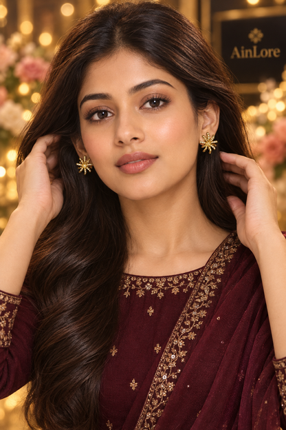 Ananya adjusting hair behind ears, showing earrings, jewel-tone outfit, bokeh backdrop