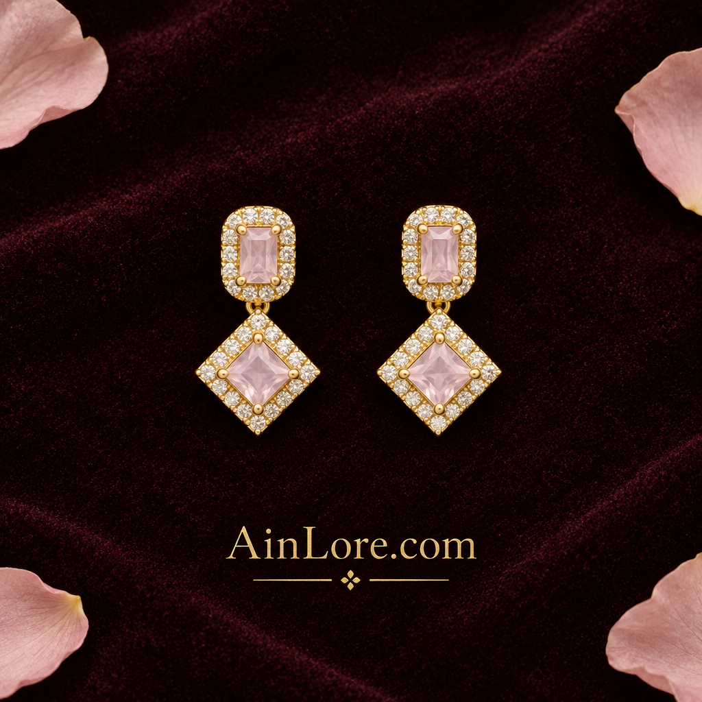 Blush-pink geometric earrings on dark fabric with petals