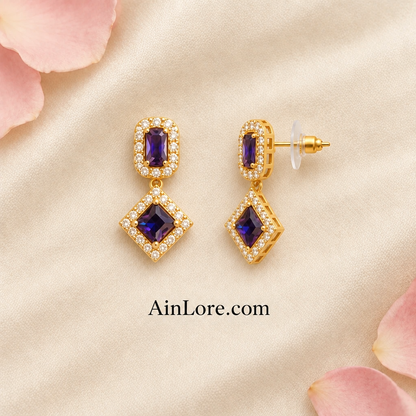 Purple geometric earrings with one tilted to show the clasp